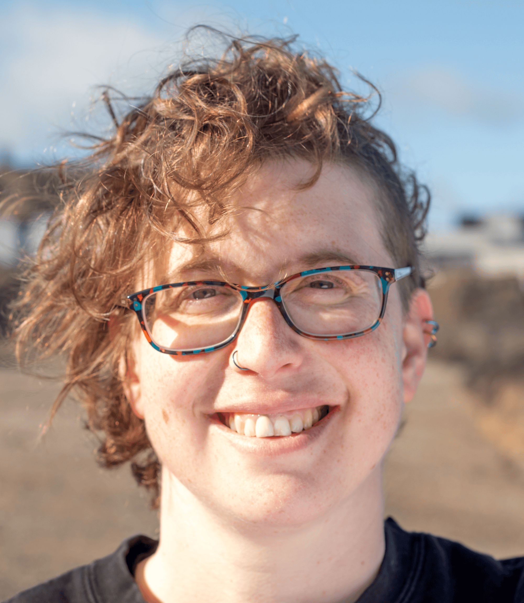 A photo of Rebs on the beach, smiling at the camera. 